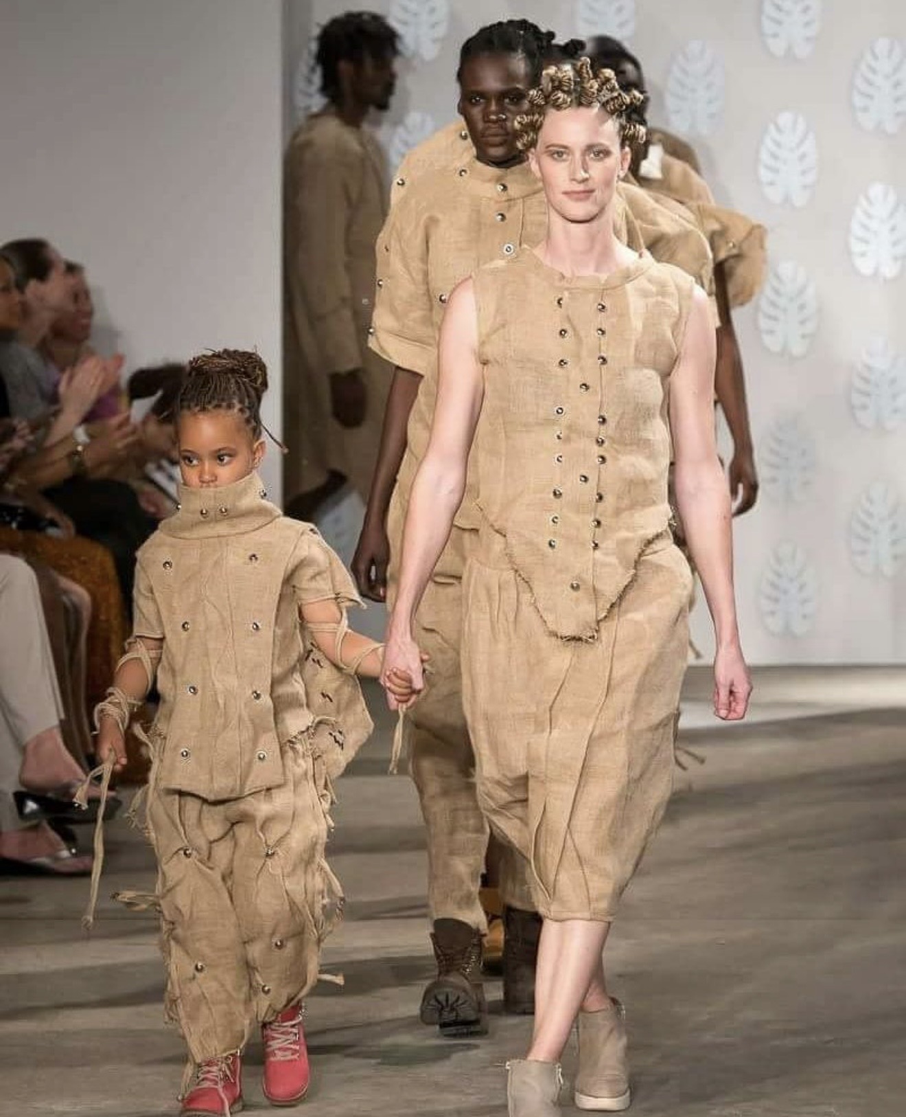 Bobbin Case runway collection — models wearing sisal sack garments with metal stud details at an international fashion show