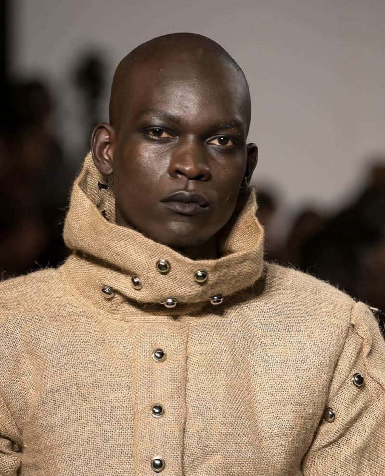 Side profile close-up of male model in sisal sack jacket with metal studded scarf wrap collar