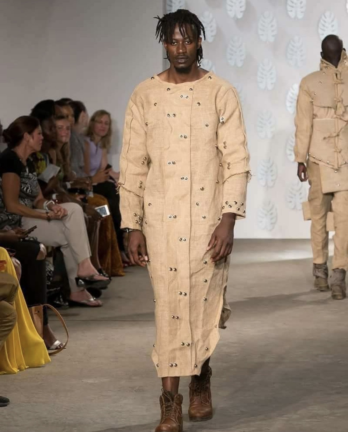 Male model wearing sisal outfit with rope and cord bindings on arms and legs at an East Africa runway show