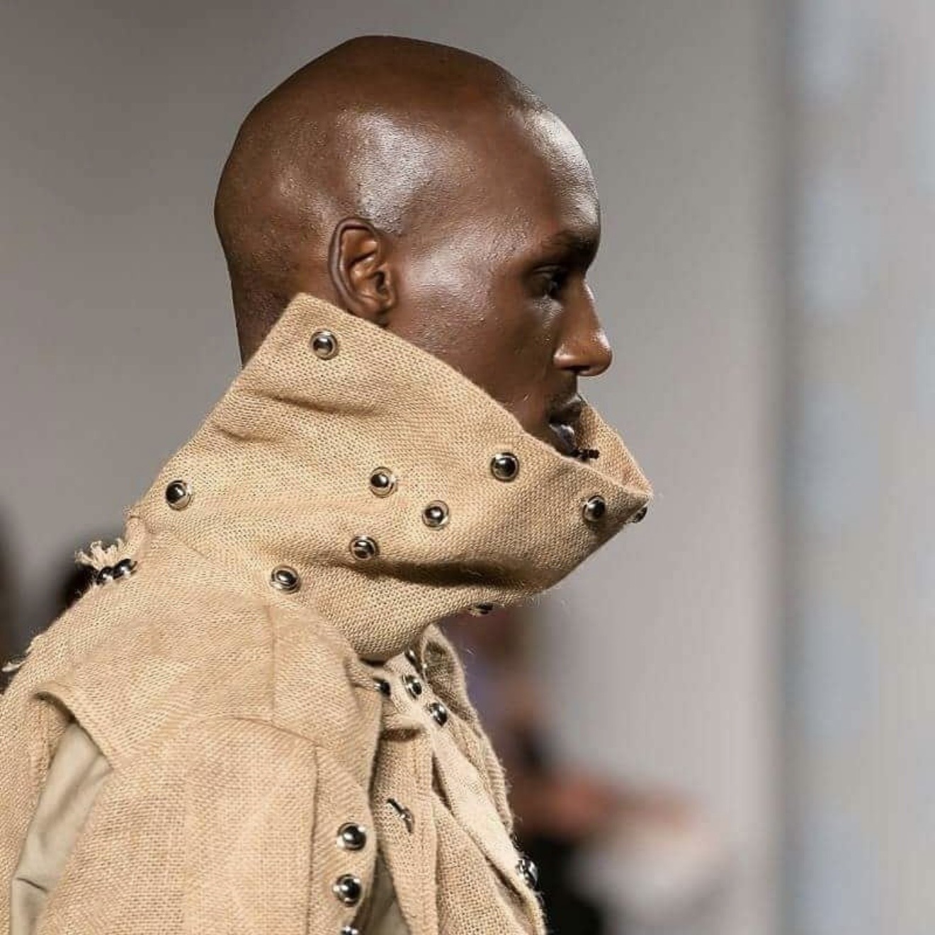 Side profile of model wearing sisal sack jacket with hand-painted African art panels and sisal headwrap