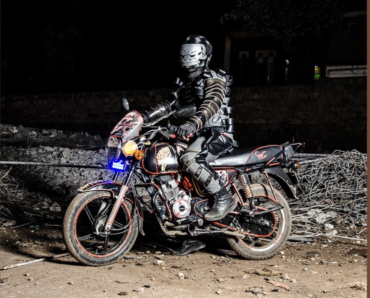 Boda Boda Madness — Nairobi motortaxi driver in all-black armoured custom outfit on a heavily decorated motorcycle at night